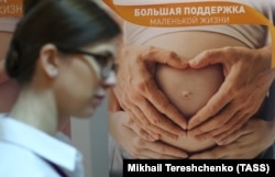 A woman walks by a poster at an event for young parents in Moscow in 2018.