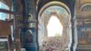 Жінка біля прапорів угруповання ДНР, намальованих на пошкодженій під час штурмів армії РФ будівлі Маріуполя, 15 липня 2022 року