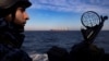 A Ukrainian coast guardsman mans a gun on a patrol boat as a cargo ship passes by in the Black Sea in February 2024. 