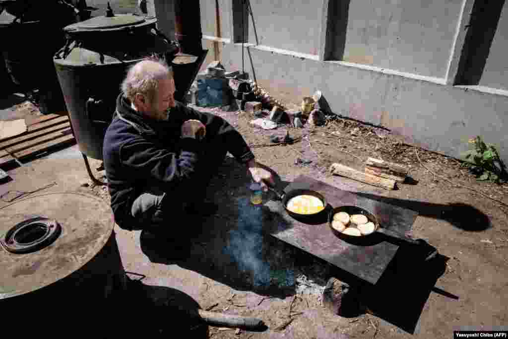 A man cooks over an open fire outside the bunker of a factory in Severodonetsk on April 27. 