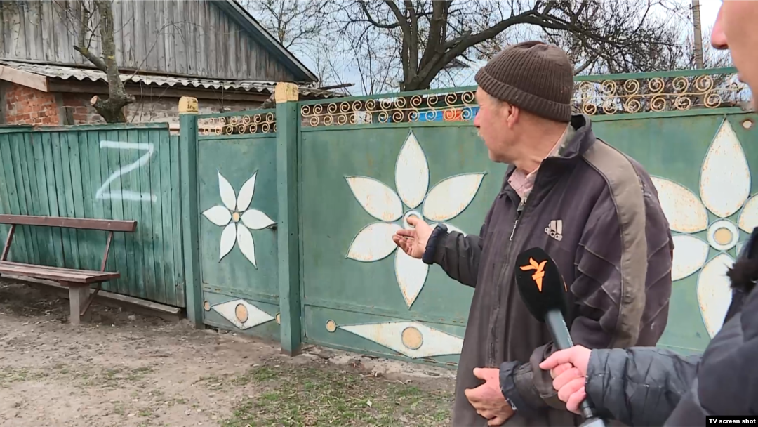Мешканець села Іванівка показує напис, який зробили на його загорожі російські солдати