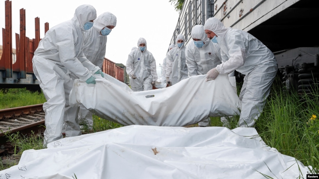 Muncitorii ucraineni transportă cadavrele soldaților ruși uciși în timpul invaziei înainte de a-i pune într-un vagon frigorific la Kiev, pe 13 mai.