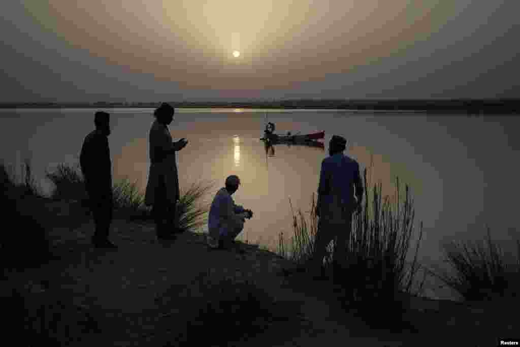 Locals watch fisherman set their nets on the Chenab River in Multan, Pakistan.