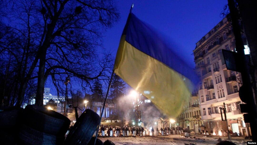 The Ukrainian national flag flies above an antigovernment barricade that faces a cordon of riot police in Kyiv on February 3.