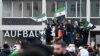 Mai mulți bărbați flutură steaguri siriene și germane în timpul unei manifestații de pe 8 decembrie, la Berlin, pentru a sărbători sfârșitul regimului lui Bashar al-Assad.