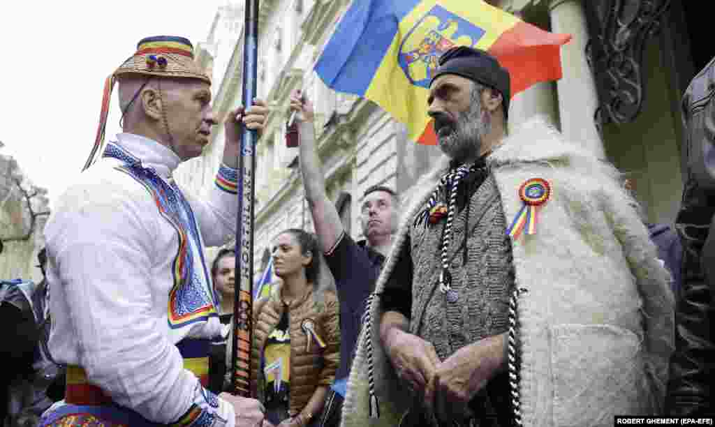 Men wearing an ancient Dacian outfit (right) and a traditional peasant suit attend a protest organized by Romanian ultranationalists in Bucharest to protest the recent cancellation of the results of the first round of a presidential election.