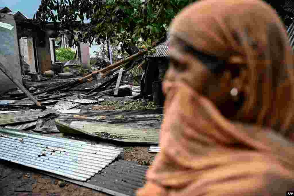 A woman stands outside a house destroyed by Pakistani artillery shelling in the village of Salamabad village in the Indian-administered part of the disputed Kashmir region.