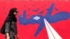 A woman walks past a mural depicting a US Air Force unmanned aerial vehicle (UAV, or drone) painted on the outer walls of the former US embassy in Tehran, colloquially-referred to as the "Spy Den," on April 8, 2025.