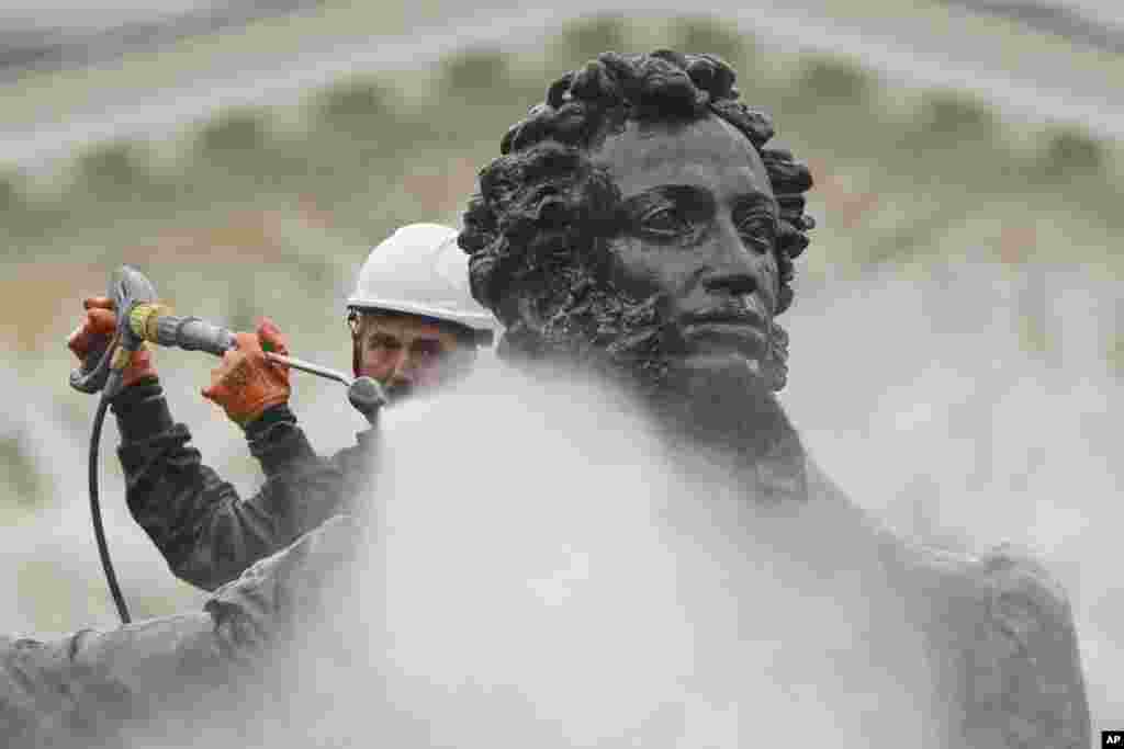 A municipal worker cleans a statue of the Russian poet Aleksandr Pushkin in St. Petersburg.
