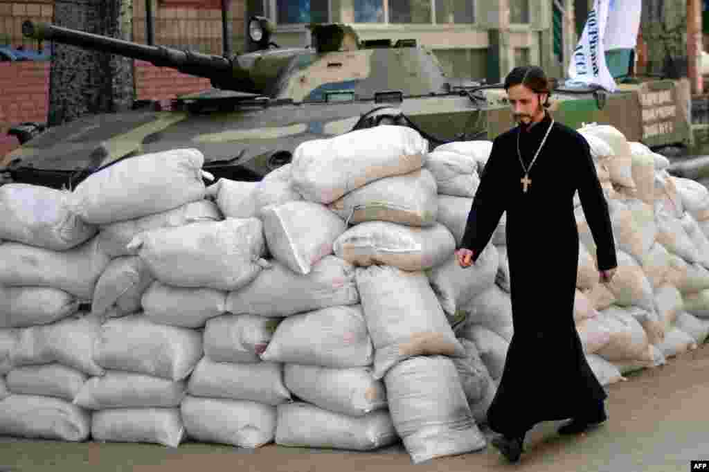 Священик проходить повз барикад біля захопленої проросійськими бойовиками будівлі СБУ у Слов'янську, 23 квітня 2014 року