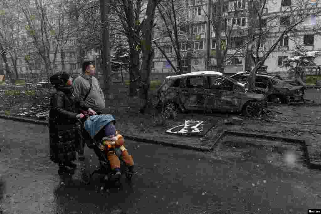 Locals pass by burned cars at the site of a Russian drone strike in Dnipro, Ukraine, on April 9.