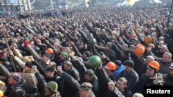 People cheer as they listen to police officers from Lviv who have joined the antigovernment protests during a rally on Independence Square in Kyiv on February 21.