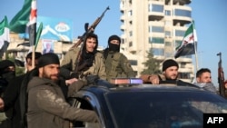 Anti-government fighters brandish their guns as they ride a vehicle in Syria's northern city of Aleppo on November 30.