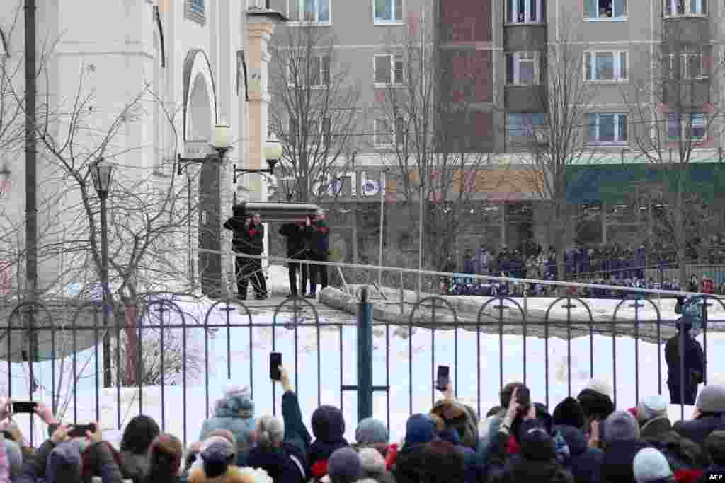 Pallbearers carry the coffin as mourners look on. 