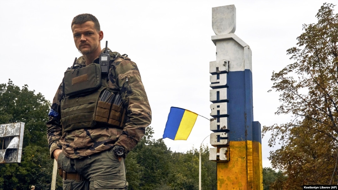 Український військовий біля знаку з написом «Куп’янськ» у відвойованому напередодні ЗСУ місті Куп’янську на Харківщині, 14 вересня 2022 року, ілюстративне фото