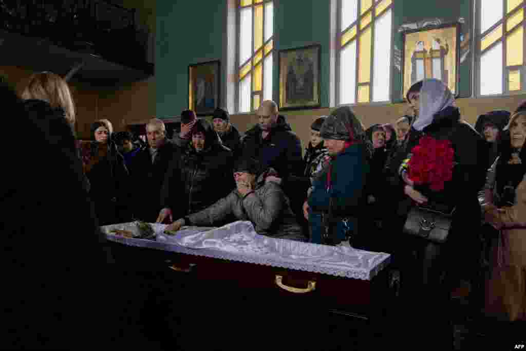 Relatives and friends mourn next to the coffin of 18-year-old Ukrainian soldier Olexandr Samoilovich during his funeral ceremony in the city of Slavuta.