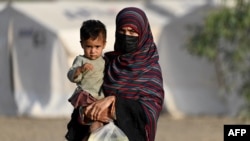 Afganistanka drži dijete dok stiže iz Pakistana u improvizirani kamp blizu afganistansko-pakistanske granice Torkham u provinciji Nangarhar 20. aprila