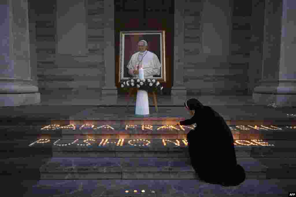 A Catholic nun lights a candle next to a portrait of the late Pope Francis displayed at the St. Mother Teresa Cathedral in the Kosovar capital, Pristina.