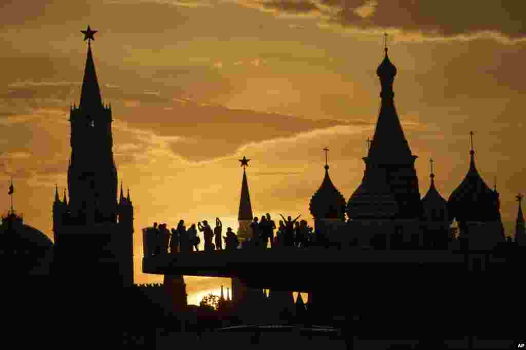 People watch and photograph a sunset behind the Kremlin at Zaryadye Park in Moscow.