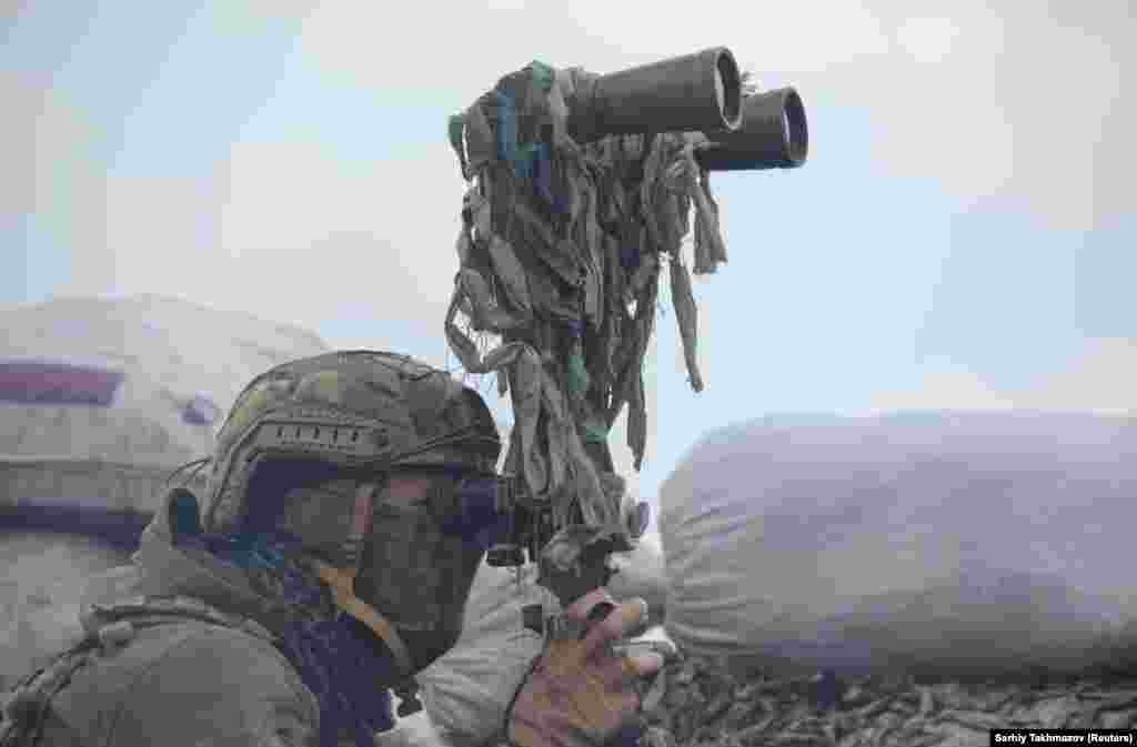A Ukrainian soldier uses binoculars while observing fighting positions on the line of separation near Donetsk on April 6. The city is under the control of Russia-backed separatists.