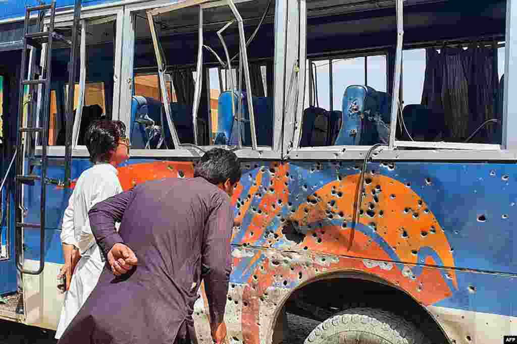 People look at a damaged Pakistani police bus parked in a security compound following a bomb explosion in the Mastung district of the restive Balochistan Province.