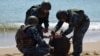 Ukrainian soldiers defuse an anti-ship mine thrown ashore by a storm in 2022.