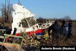 Workers move a piece of wreckage from Malaysia Airlines flight MH17 at the site of the plane crash near the village of Hrabove, Ukraine, on November 20, 2014.