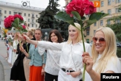 Women hold flowers during a demonstration against violence in Minsk on August 20, 2020.