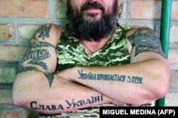 Український військовослужбовець демонструє свої руки з татуюваннями «Слава Україні» і «Україна починається з тебе». Донеччина, 9 липня 2022 року