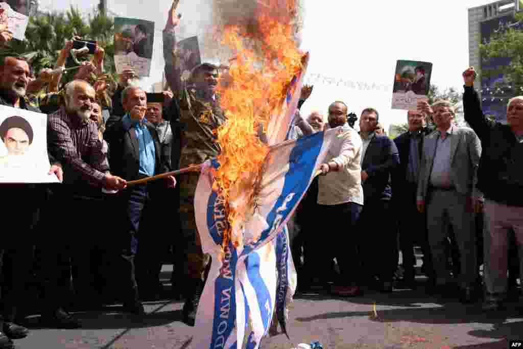 Iranian protesters set Israeli flags on fire during a rally on Tehran's Palestine Square on to denounce Israel's resumption last month of massive military operations in the Gaza Strip.