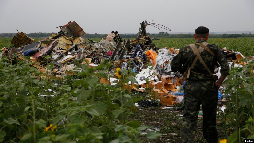 Бойовик угруповання «ДНР», яке в Україні визнано терорестичним, розглядає уламки від носової частинини «Боїнга-777», Донецька область, 18 липня 2014 року