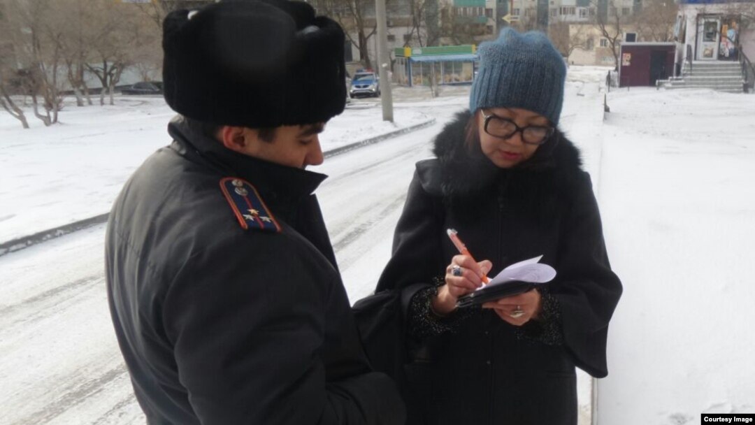 Репортеру Азаттыка Сание Тойкен полицейский вручает повестку на допрос в качестве свидетеля в ДВД Мангистауской области. Актау, 17 февраля 2017 года.