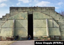 Two hobby pilots slow the movement of an armored door after opening a Soviet-made aircraft hangar at the Milovice airfield.