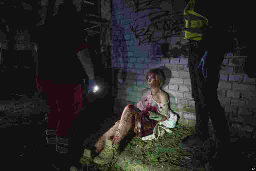 An injured woman sits near her house, which was damaged by a Russian air strike in Kyiv.