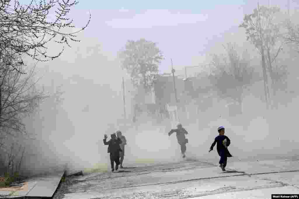 Afghan children run amid a cloud of dust as a military helicopter lands in the Green Zone in Kabul.