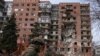 Украинский военный на фоне разрушенного при обстрелах жилого дома в Покровске (Донецкая область)