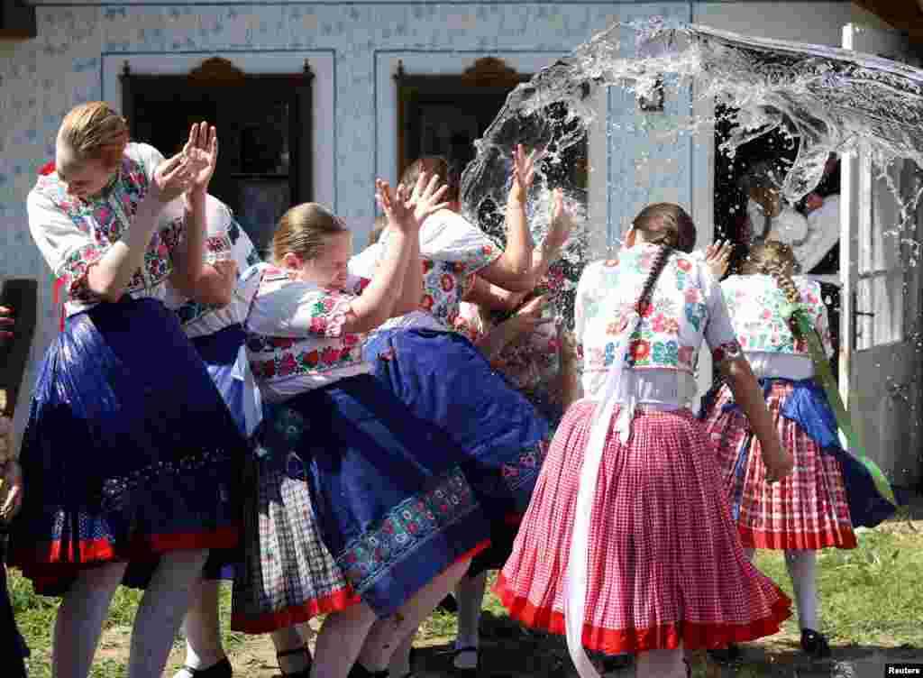 Young girls dressed in traditional clothes react as men throw water at them during a traditional Easter celebration in Csomor, Hungary, on April 21.