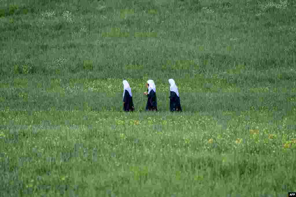 Afghan schoolgirls walk through a field in the Fayzabad district of Badakhshan Province.
