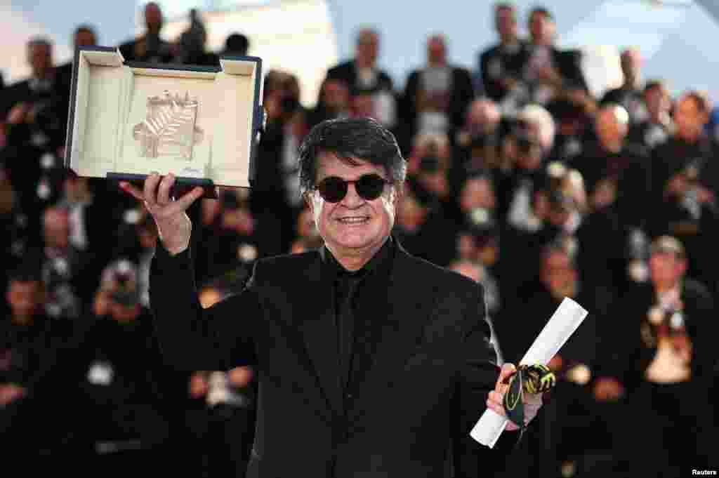Iranian director Jafar Panahi holds up the Palme d'Or award he won for his movie It Was Just An Accident at the Cannes Film Festival in France.