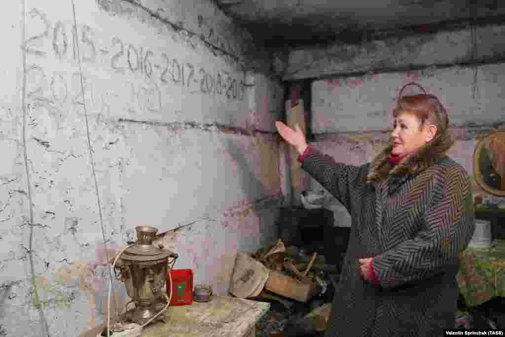 A woman points to dates written on the wall in a bomb shelter in Yasynuvata. The dates refer to New Year&#39;s parties that she and other local people celebrated there.
