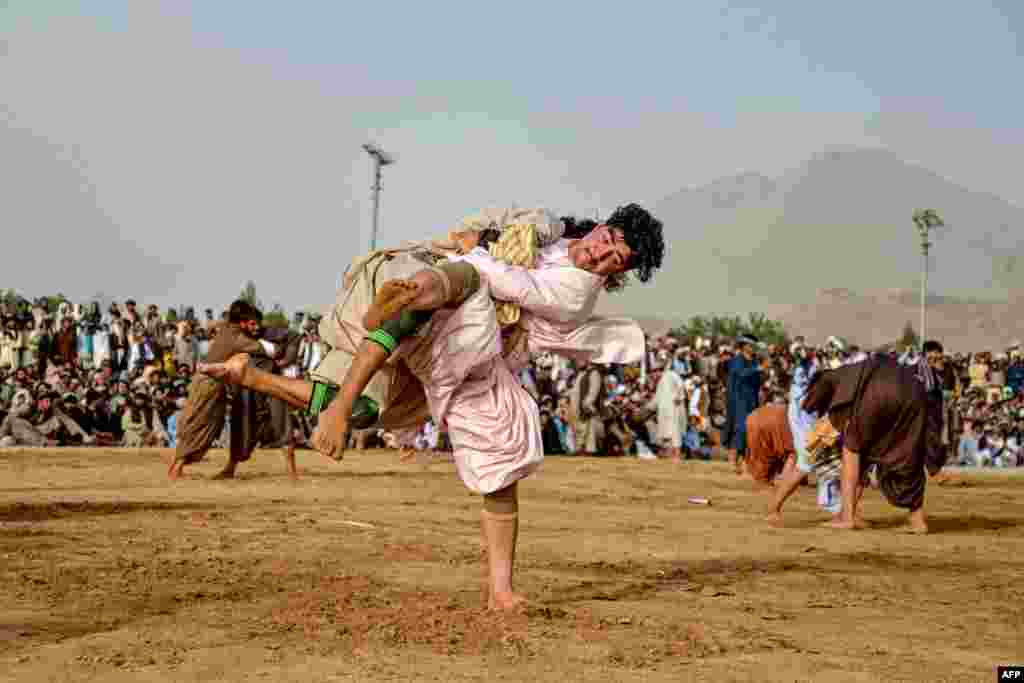 Afghan wrestlers compete during a traditional wrestling competition at a field in the Arghandab district of Kandahar Province.